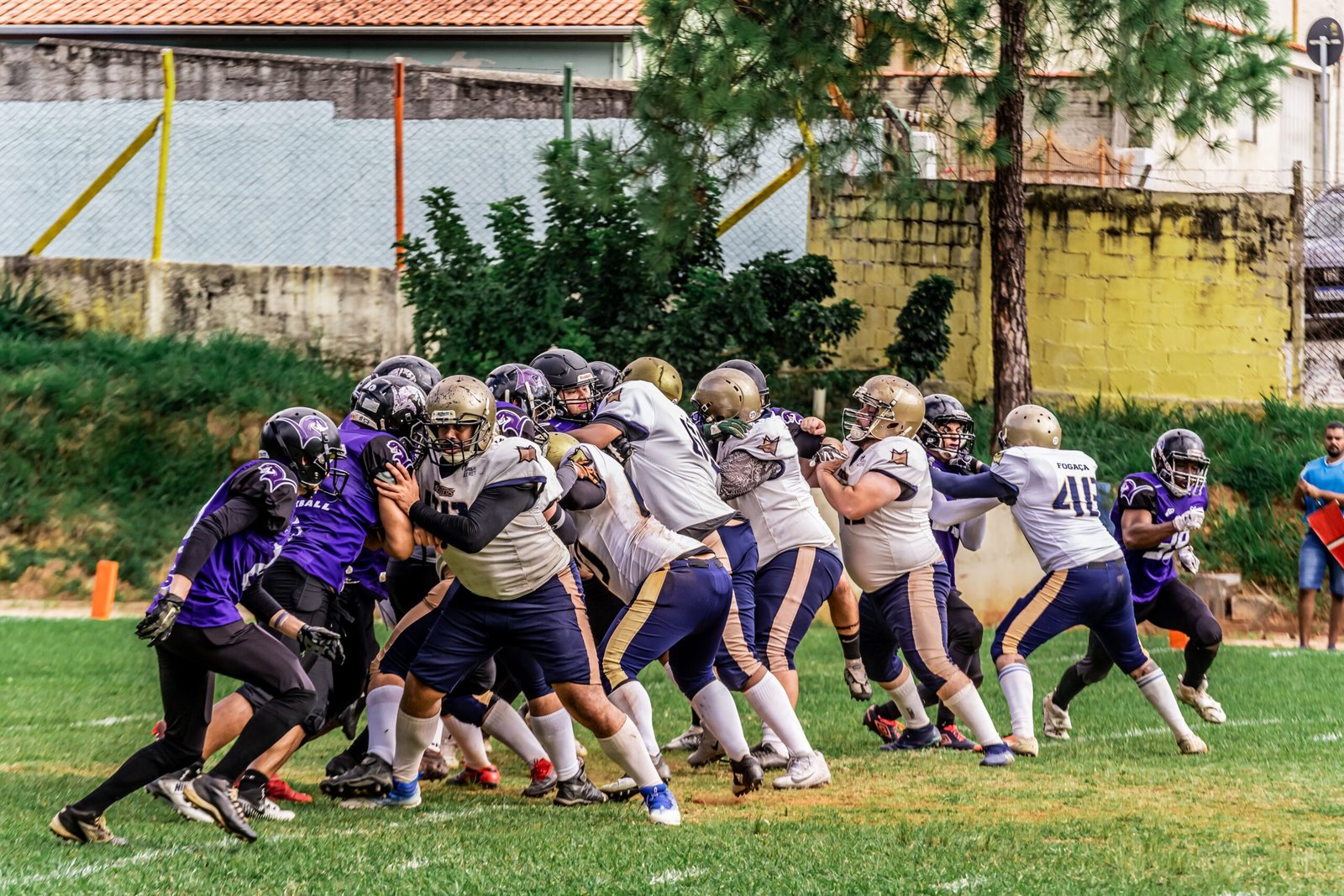 Football players in colorful uniforms compete during a sunny outdoor game.